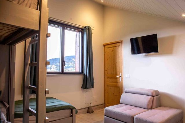 Chambre à l'étage, lit double, poutres apparentes.